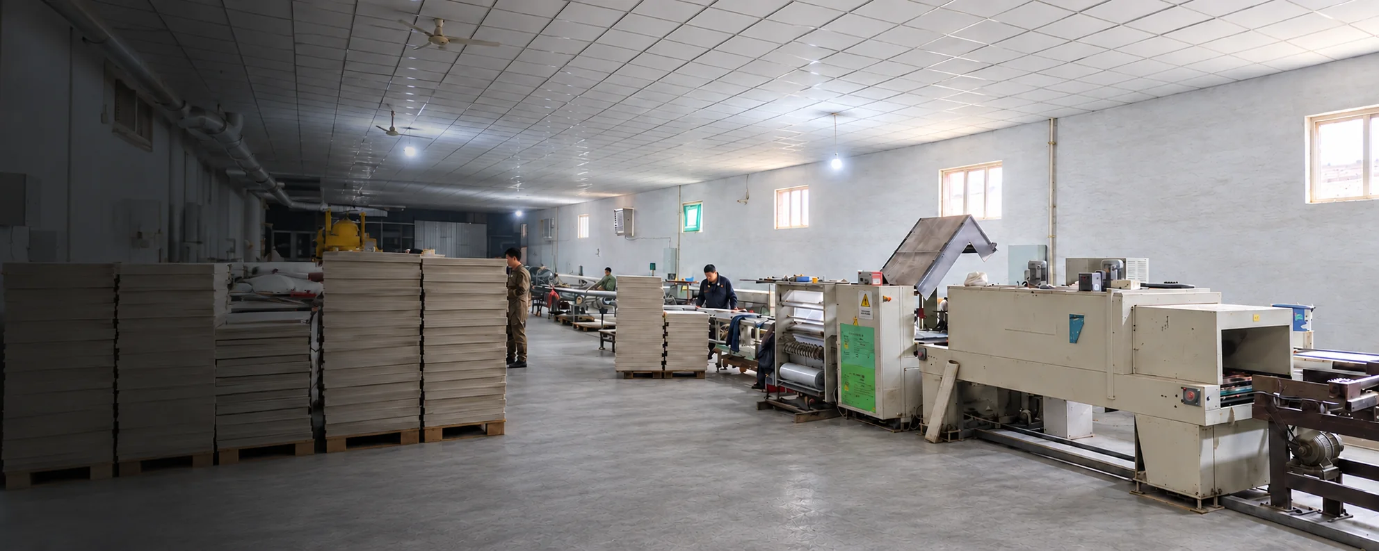 Ceiling board workshop with stacked panels, processing equipment and factory team
